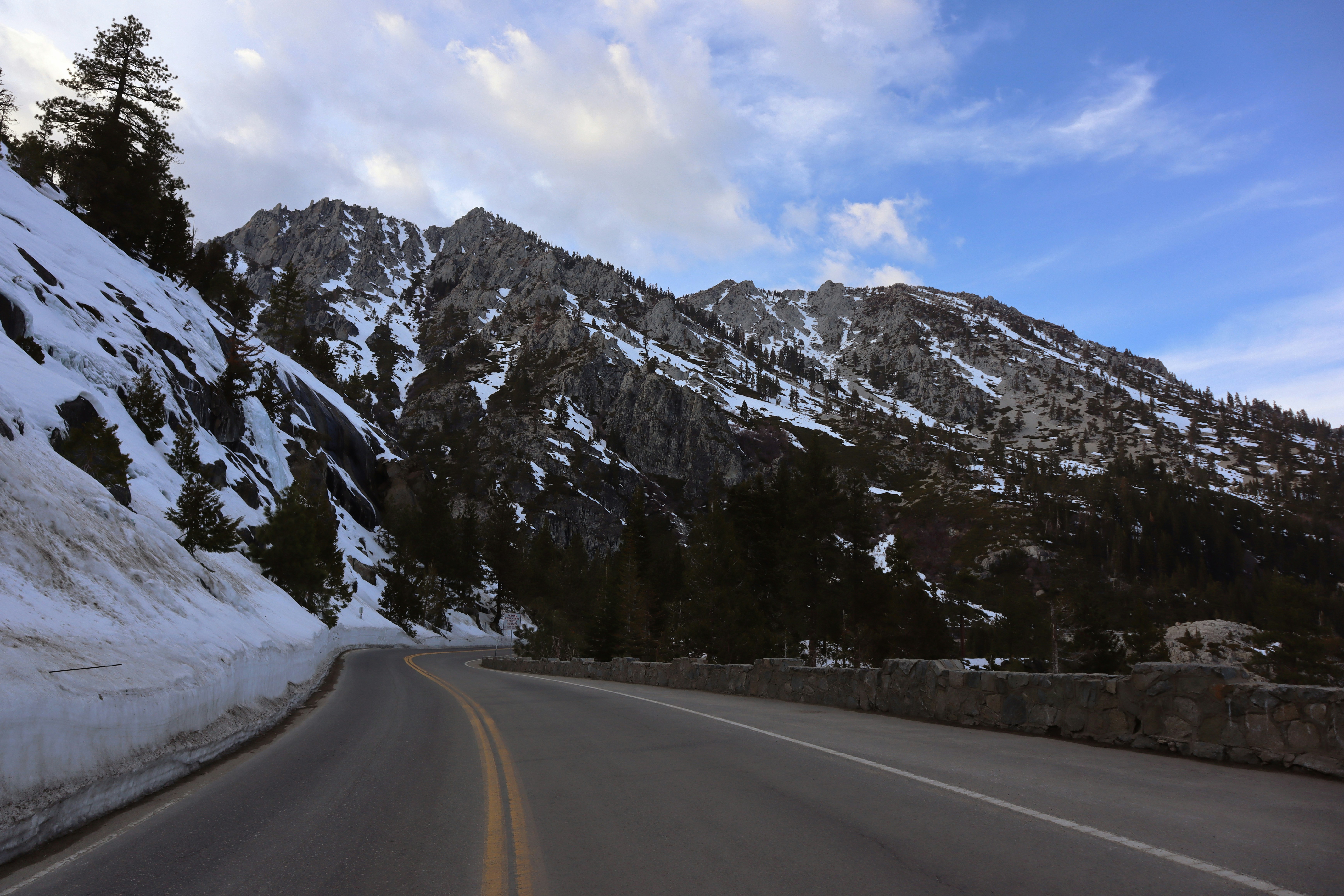 a road with snow on the side and mountains in the background