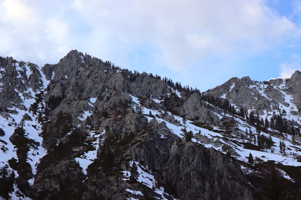 a mountain covered in snow under a cloudy blue sky