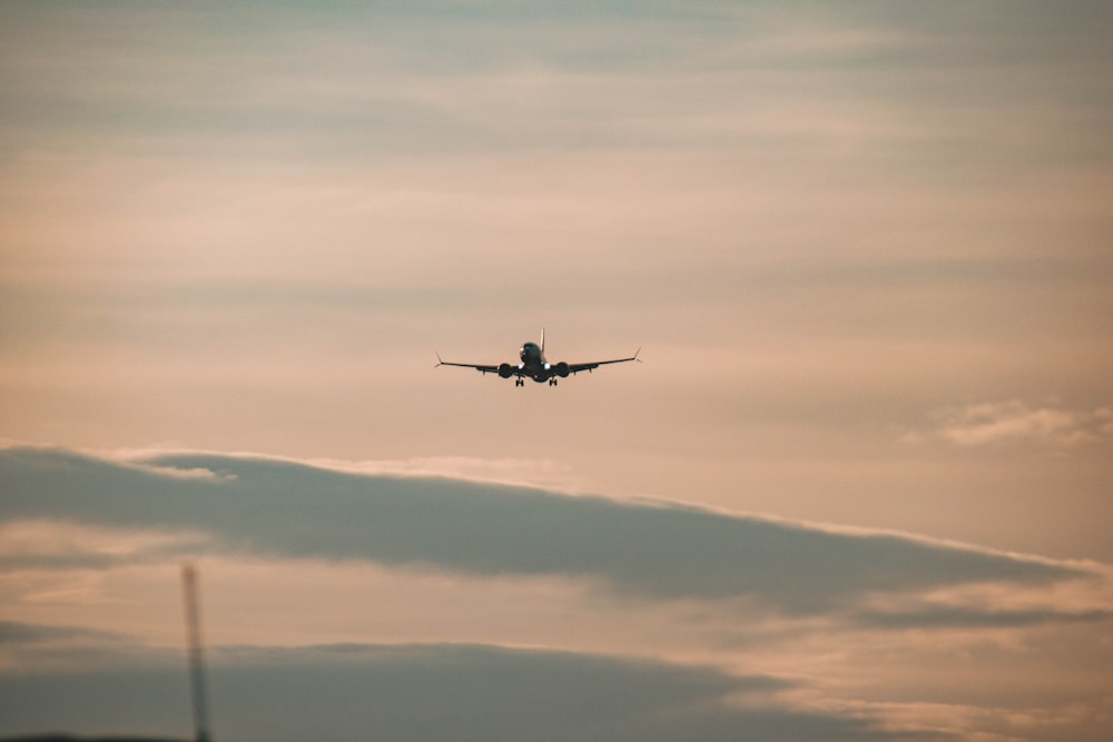 an airplane is flying in the sky at sunset