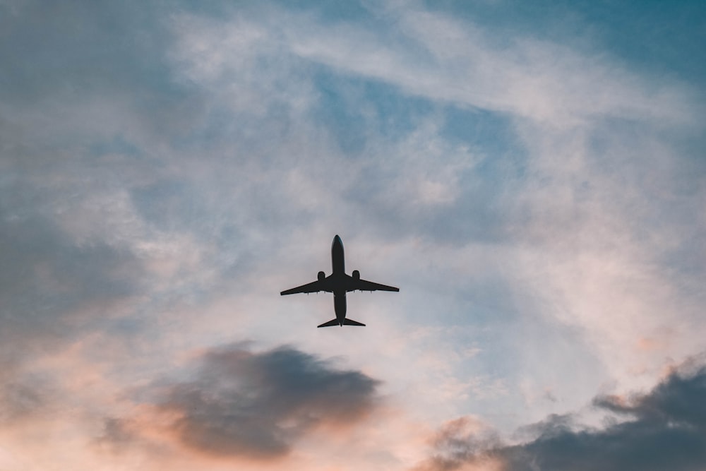 an airplane is flying in the sky at sunset