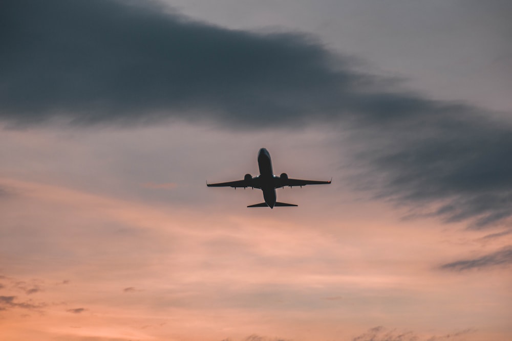 an airplane is flying in the sky at sunset