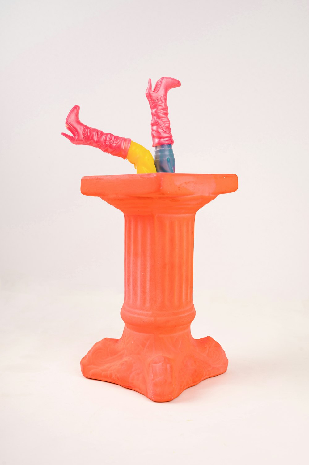 an orange vase with a pair of umbrellas sticking out of it