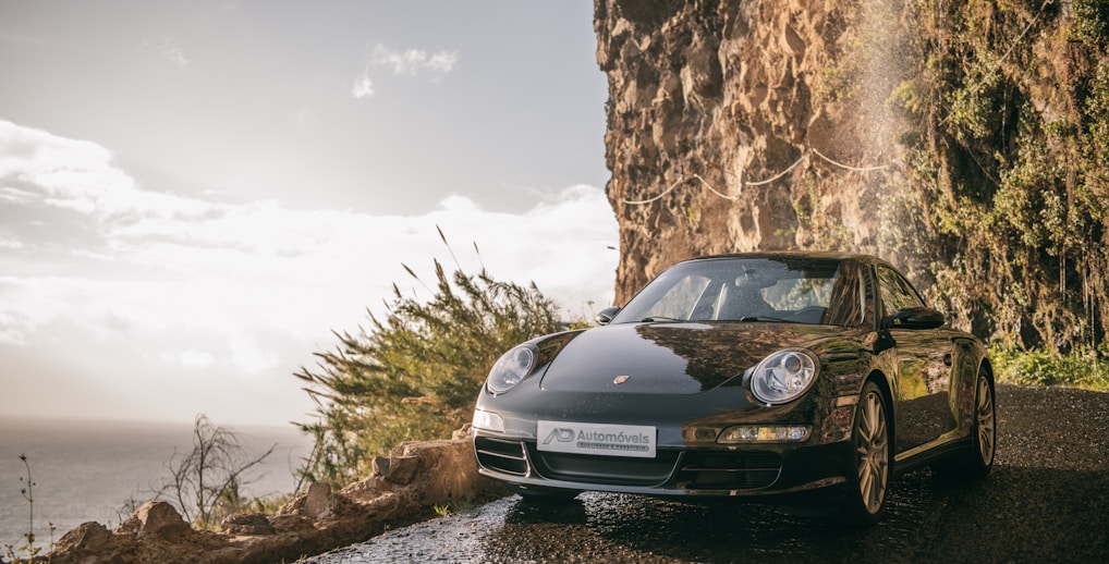 A sleek Cadillac glistening under the Spanish sun, parked on a coastal road.