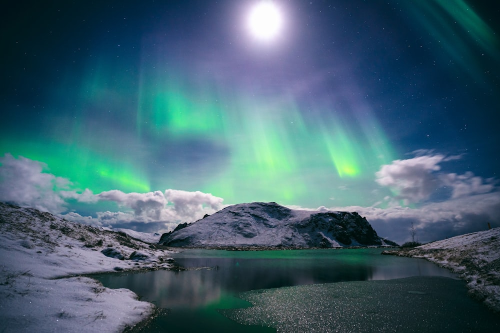 Eine grüne und blaue Aurora bohrt sich über einen See