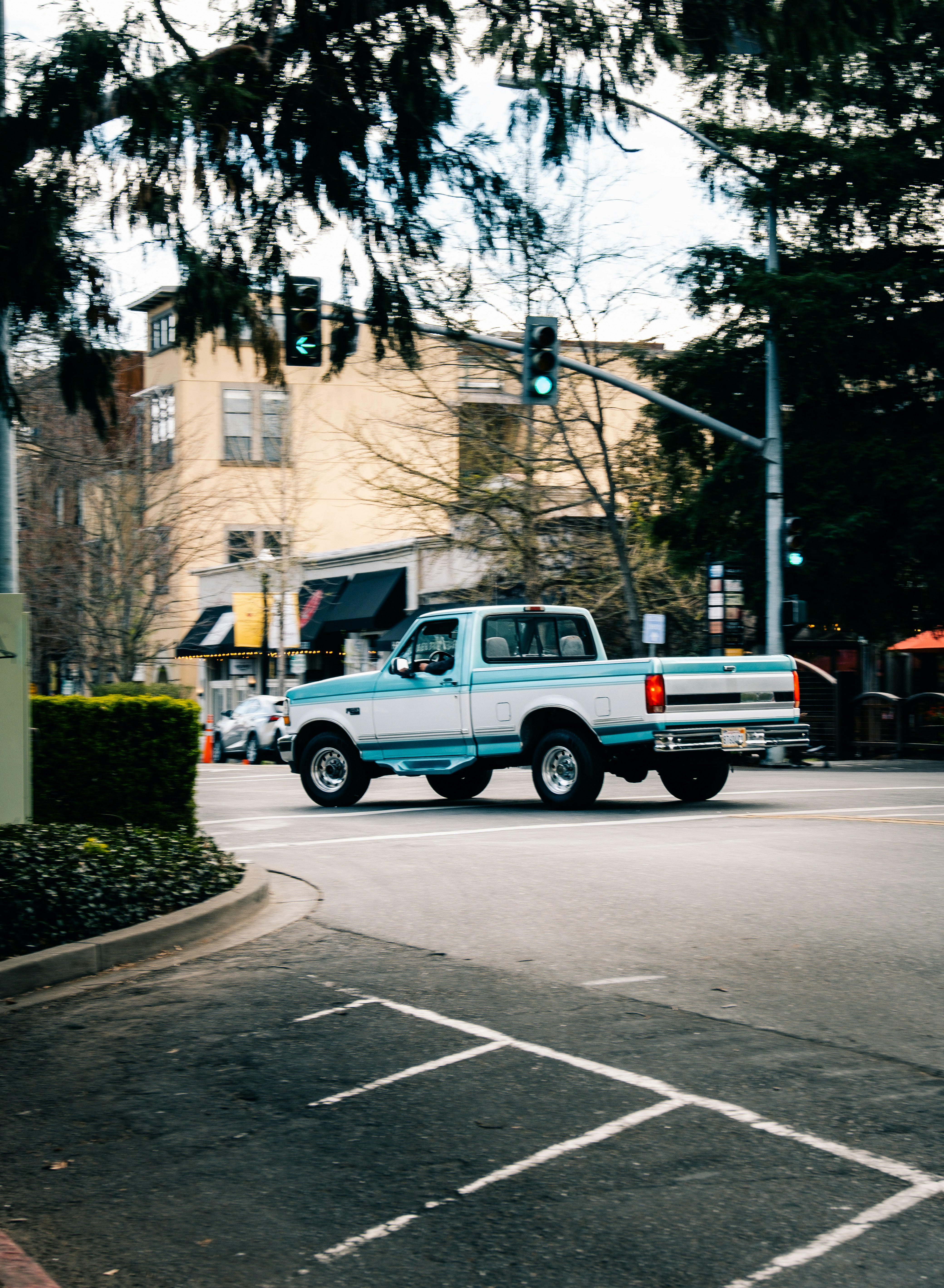 a white truck driving down a street next to a traffic light