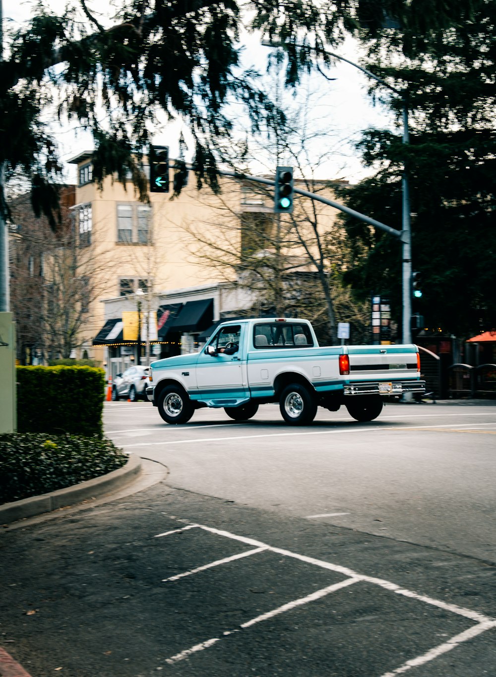 a white truck driving down a street next to a traffic light