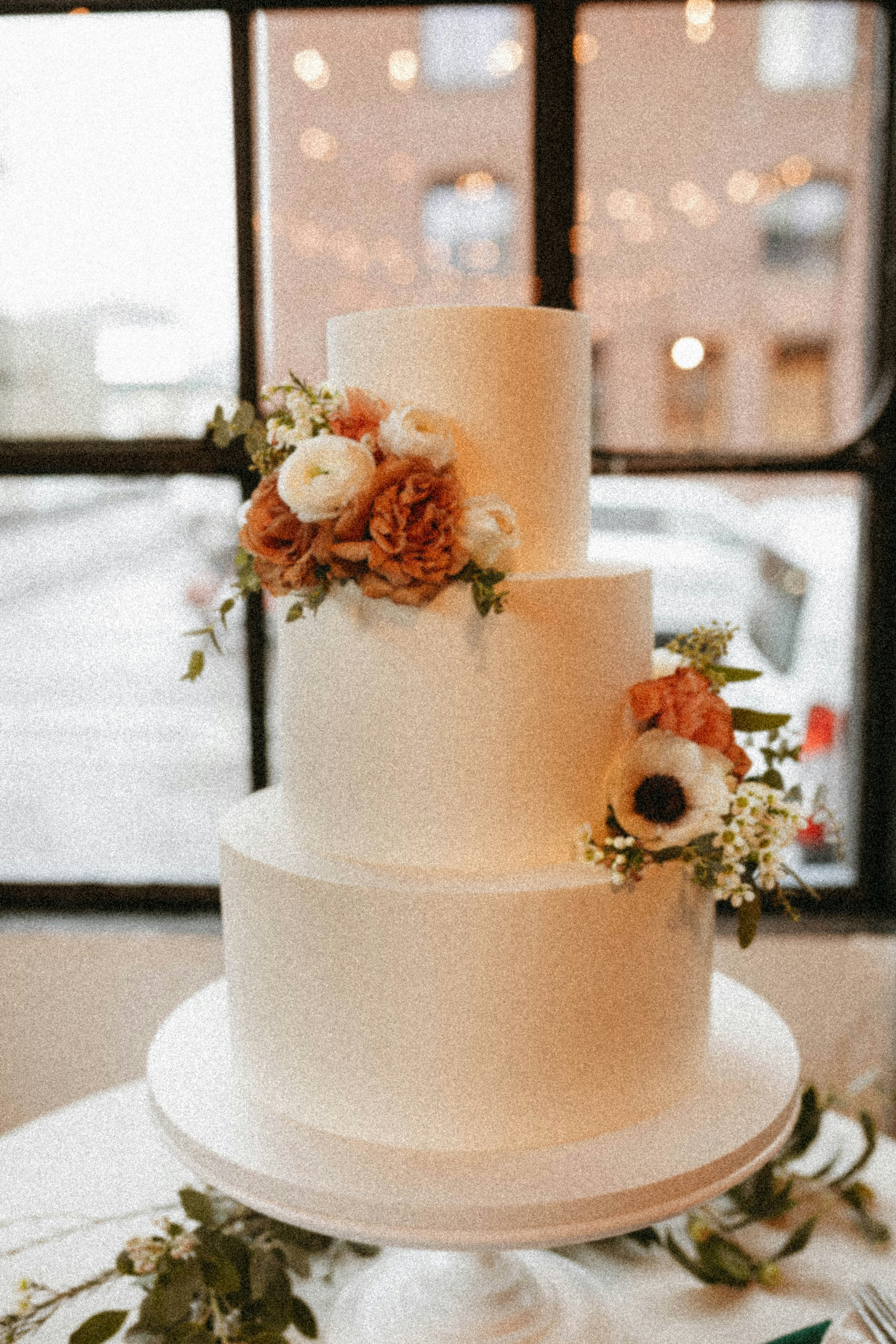 a three tiered white wedding cake with flowers on top