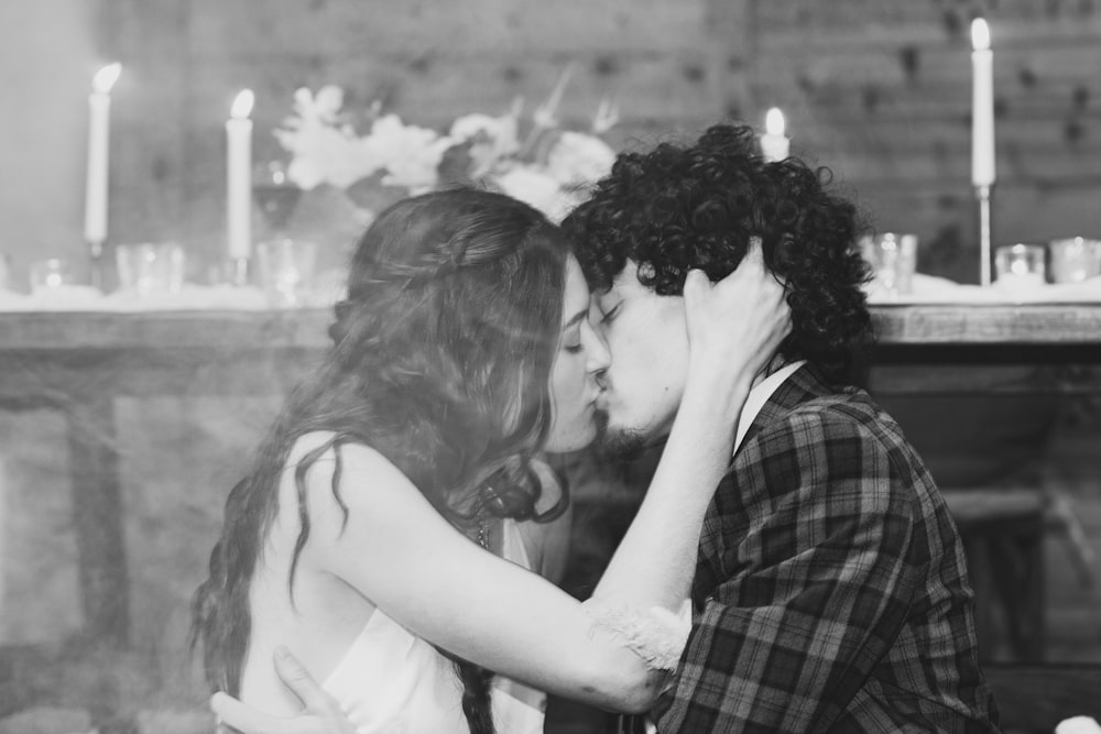 a man and a woman kissing in front of a fireplace