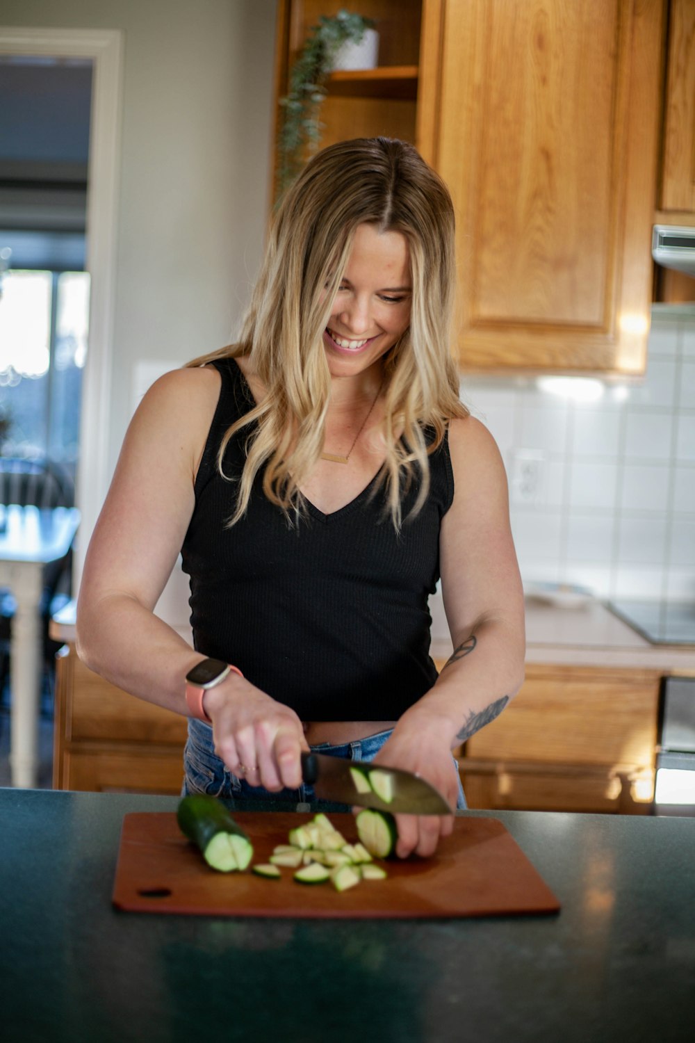 a woman in a kitchen cutting up vegetables on a cutting board