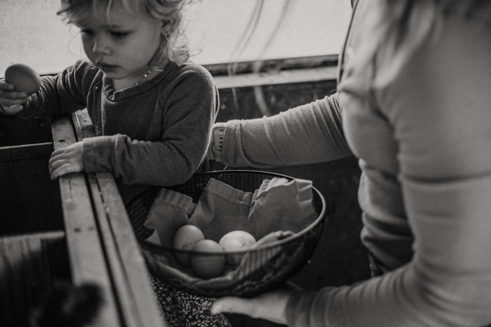 a little girl sitting in a basket of eggs