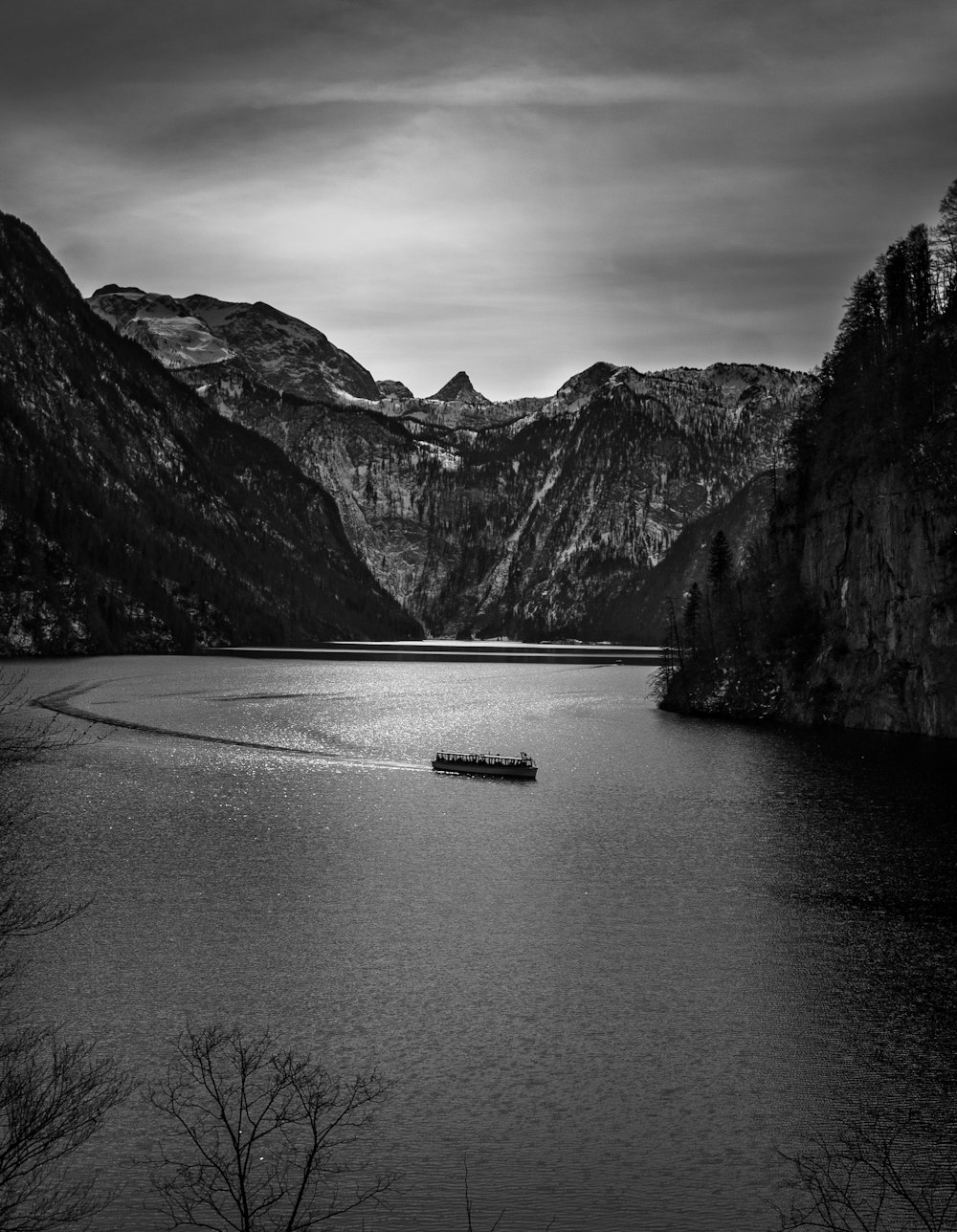 a boat floating on top of a lake surrounded by mountains