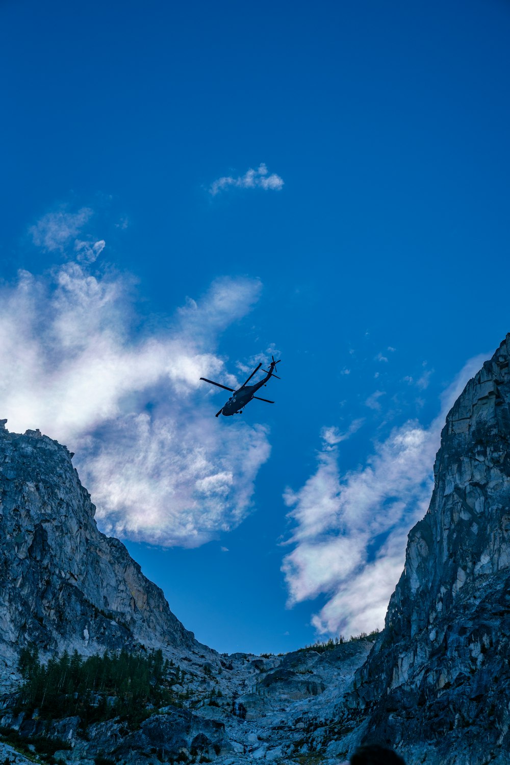 a helicopter flying over a rocky mountain range