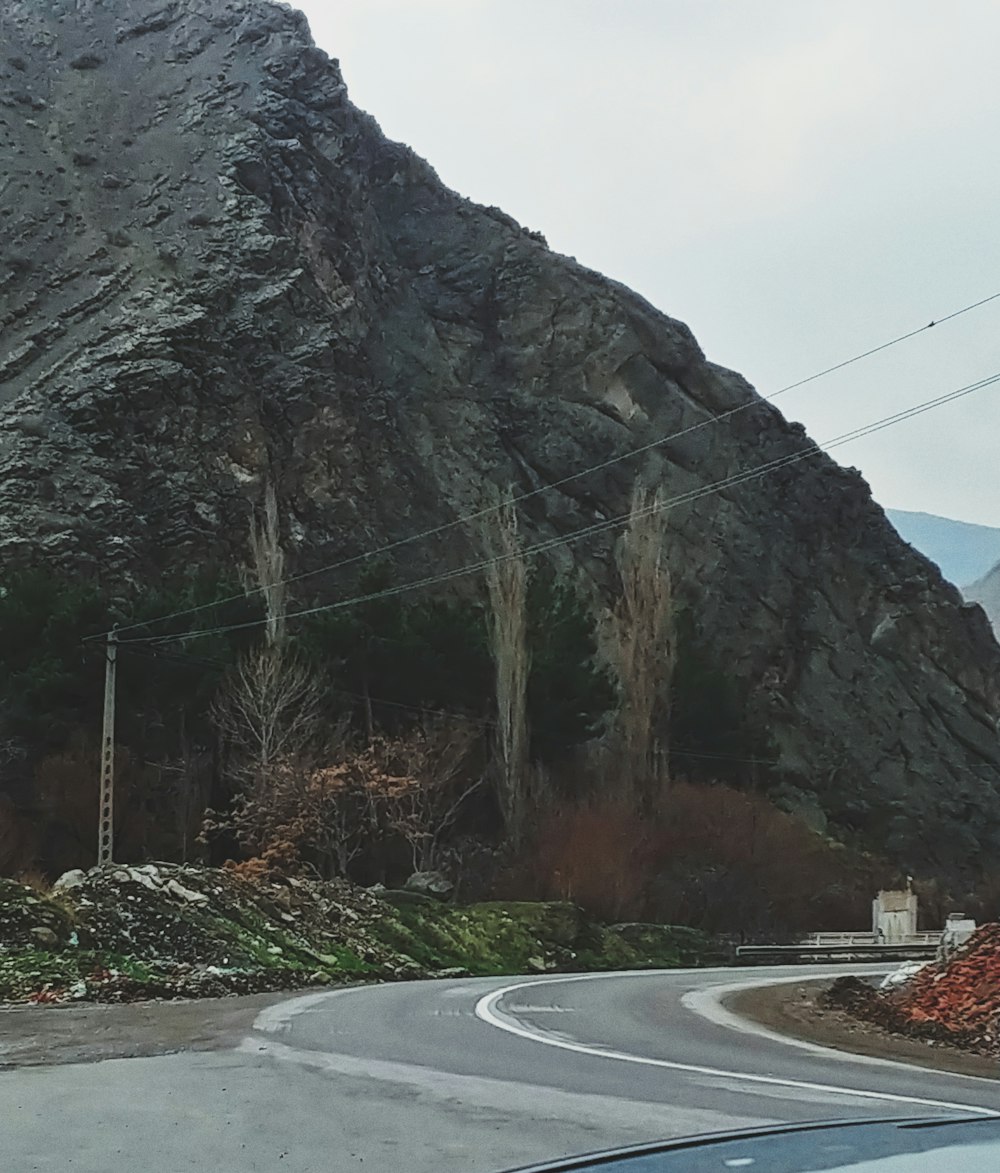 a car driving down a road next to a mountain