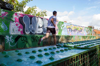 a man running across a bridge covered in graffiti