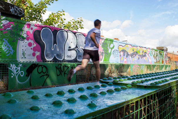 a man running across a bridge covered in graffiti