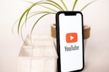 a phone with a youtube logo on it next to a potted plant