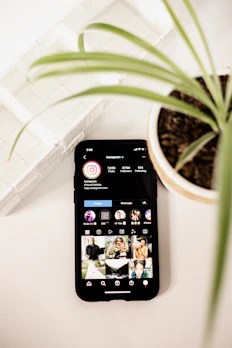 a cell phone sitting on top of a table next to a potted plant
