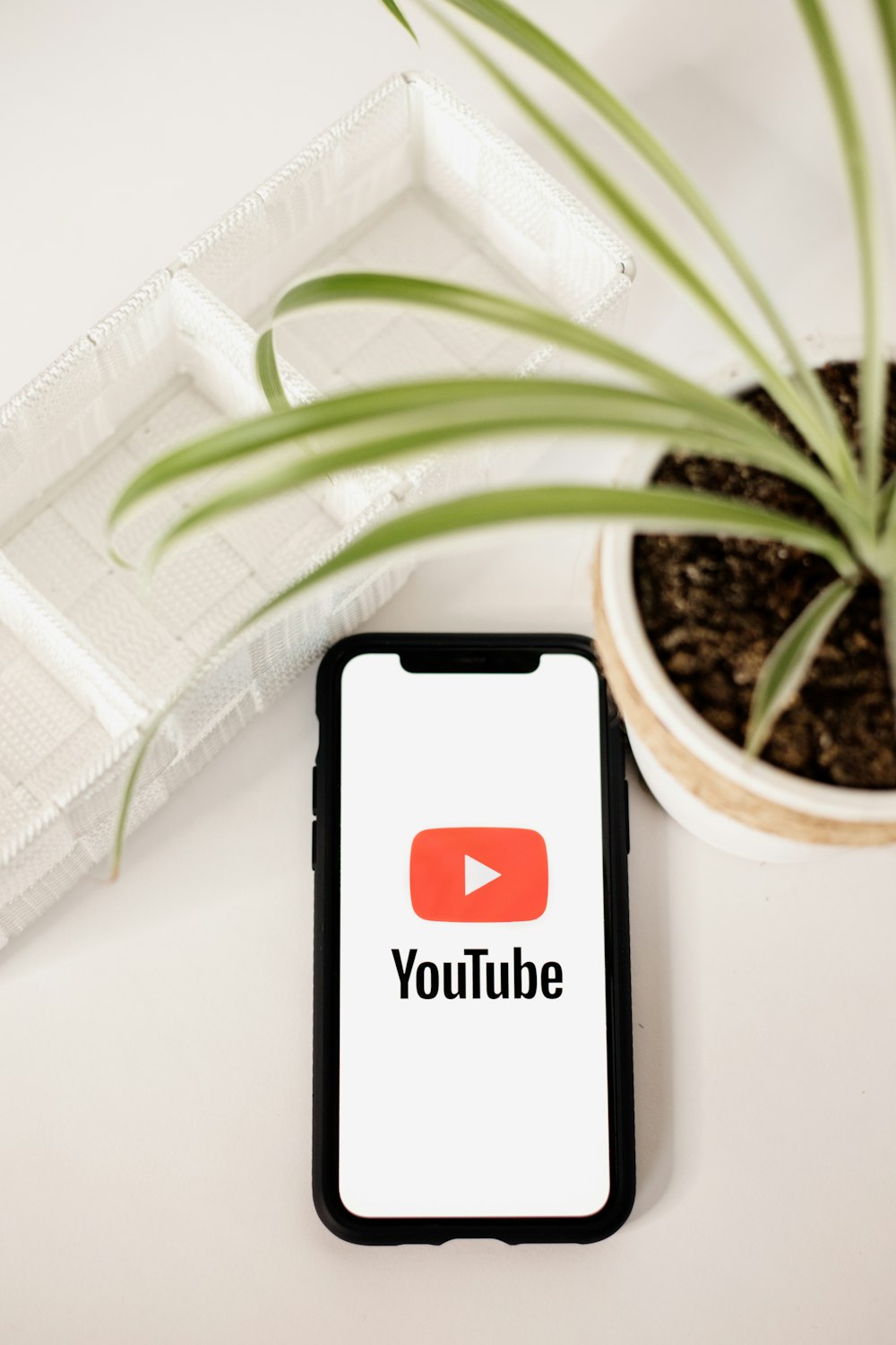 a phone with a youtube logo on it next to a potted plant