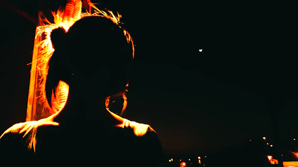 A shadowy figure standing beneath a swirling indigo nebula, illuminated by soft golden light.