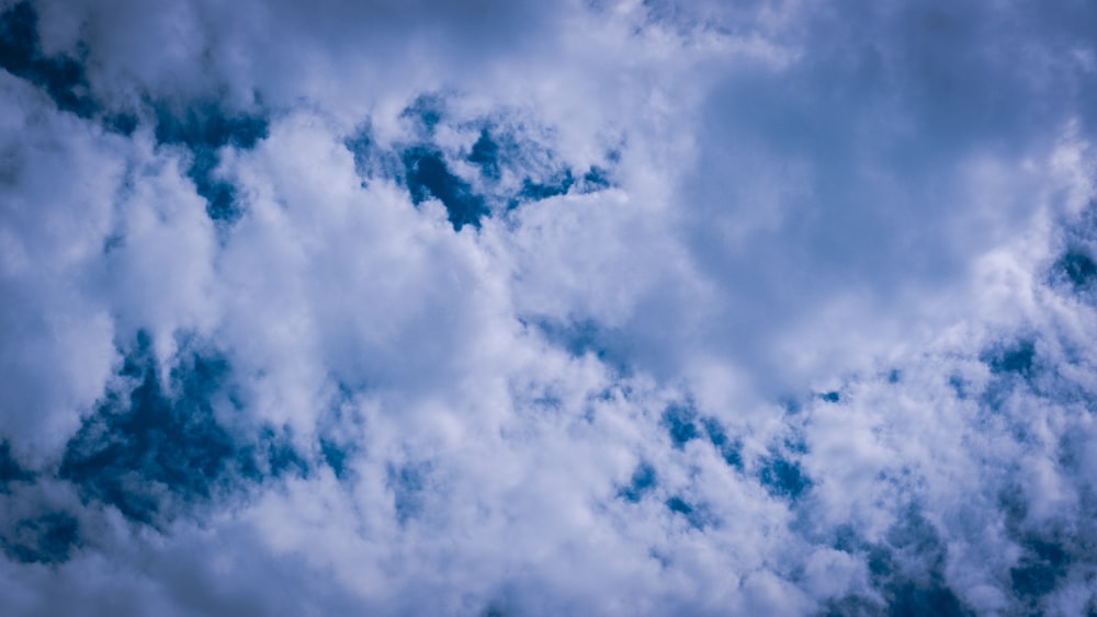 a plane flying through a cloudy blue sky