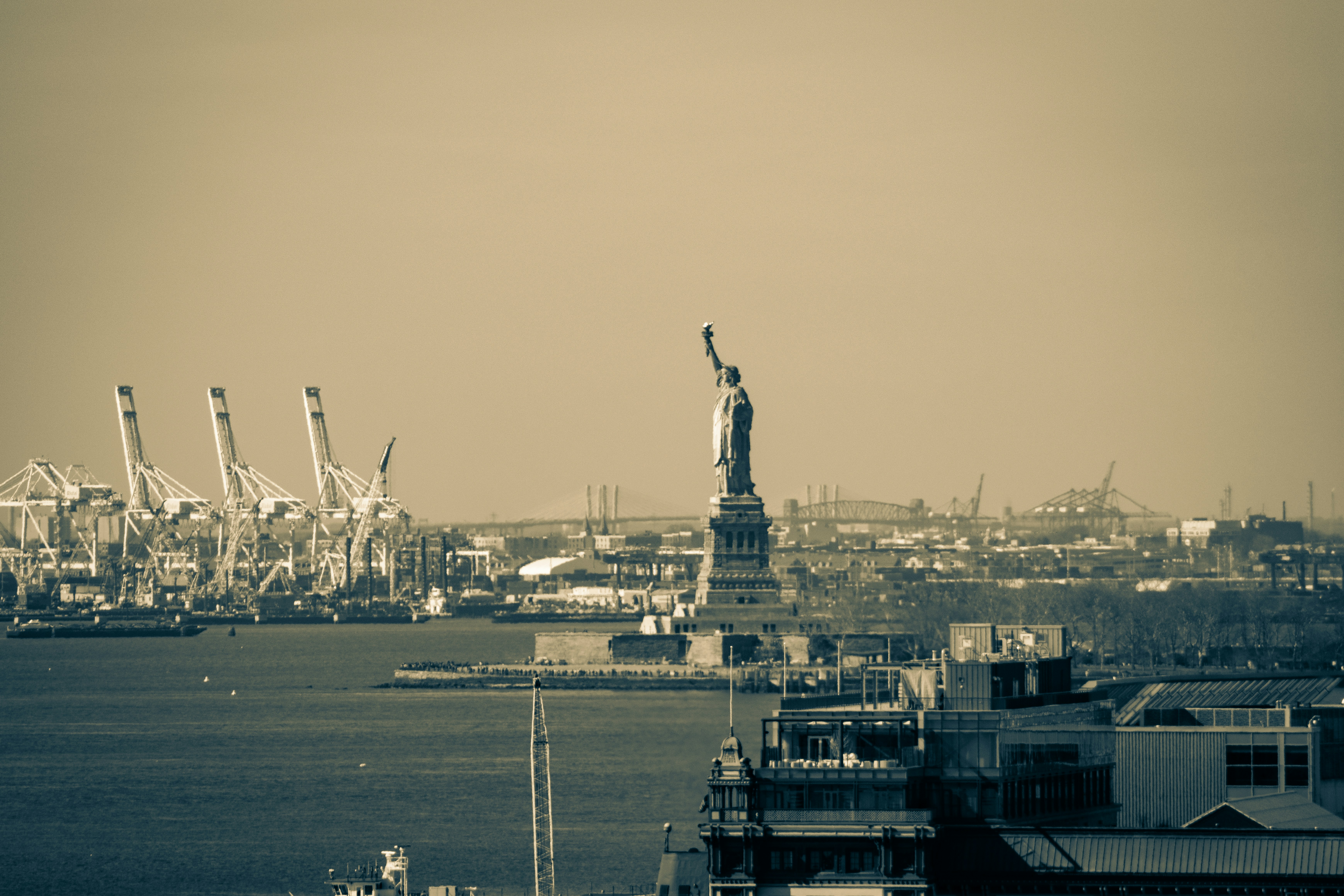 a statue of liberty stands in the middle of a harbor