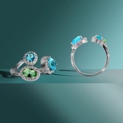 Elegant rings with green stones arranged on a white and gold decorative tray.
