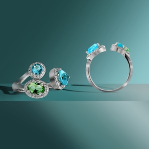 Elegant rings with green stones arranged on a white and gold decorative tray.
