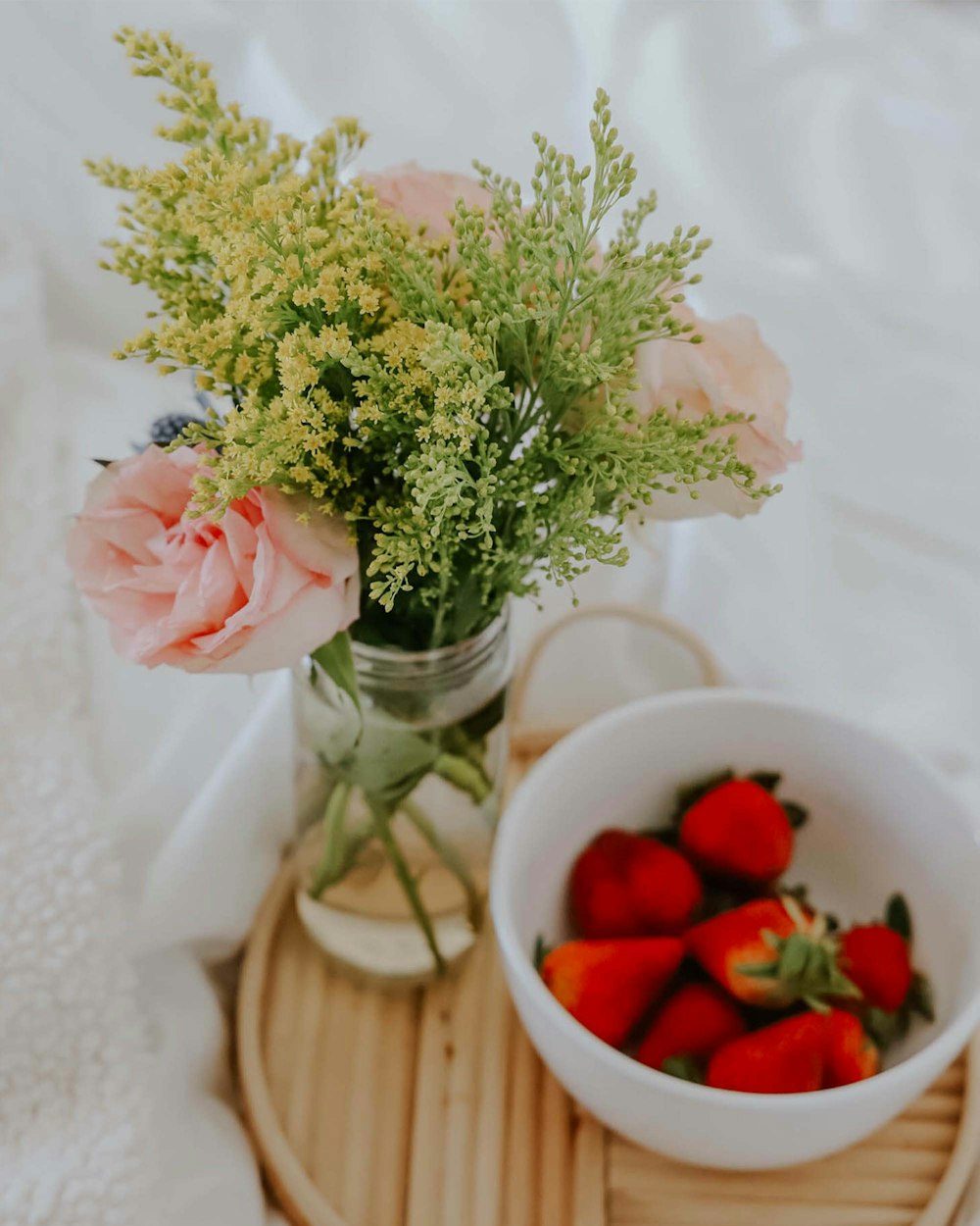 a bowl of strawberries and a vase of flowers