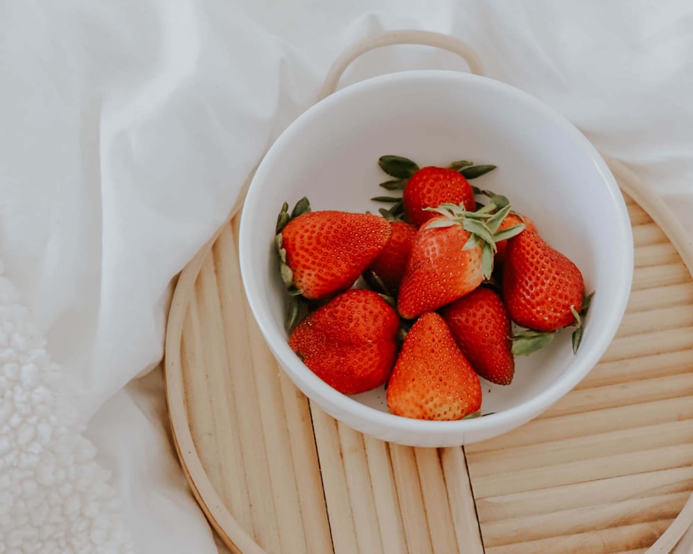 a bowl of strawberries on a wooden tray