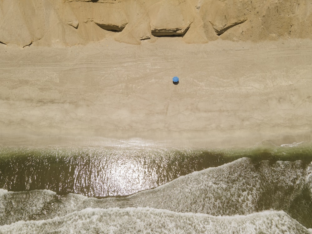 a blue ball sitting on top of a sandy beach