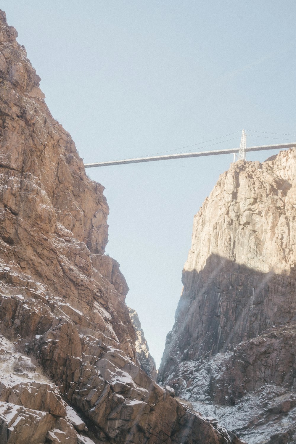 a man riding a snowboard across a suspension bridge