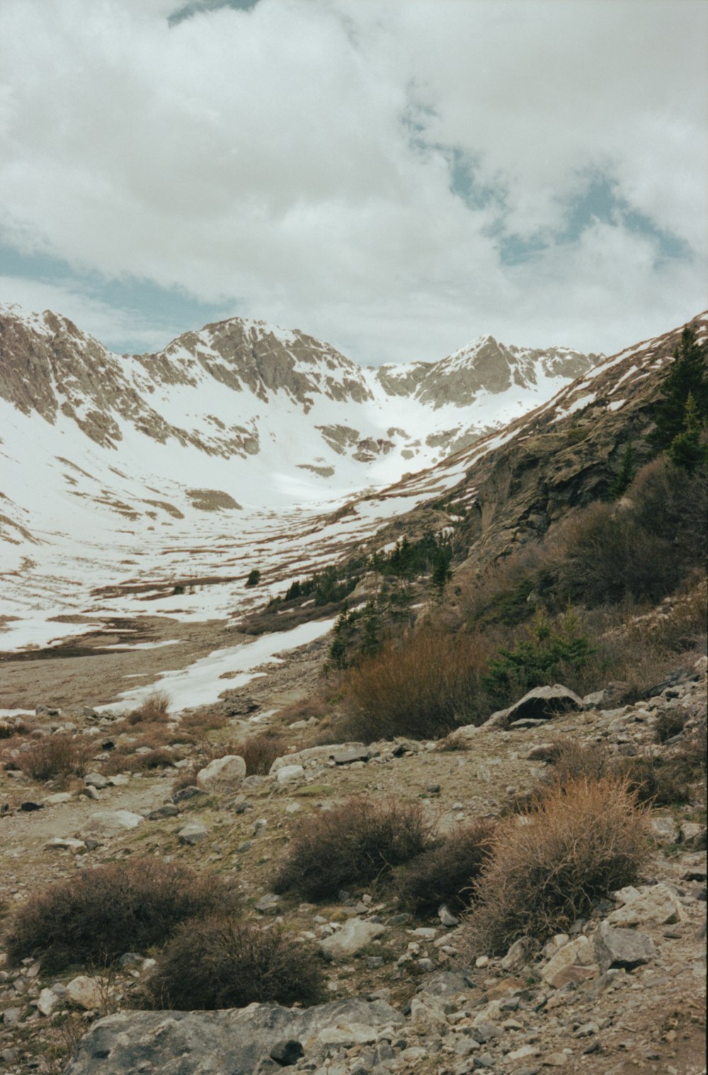 a rocky mountain with a snow covered mountain in the background