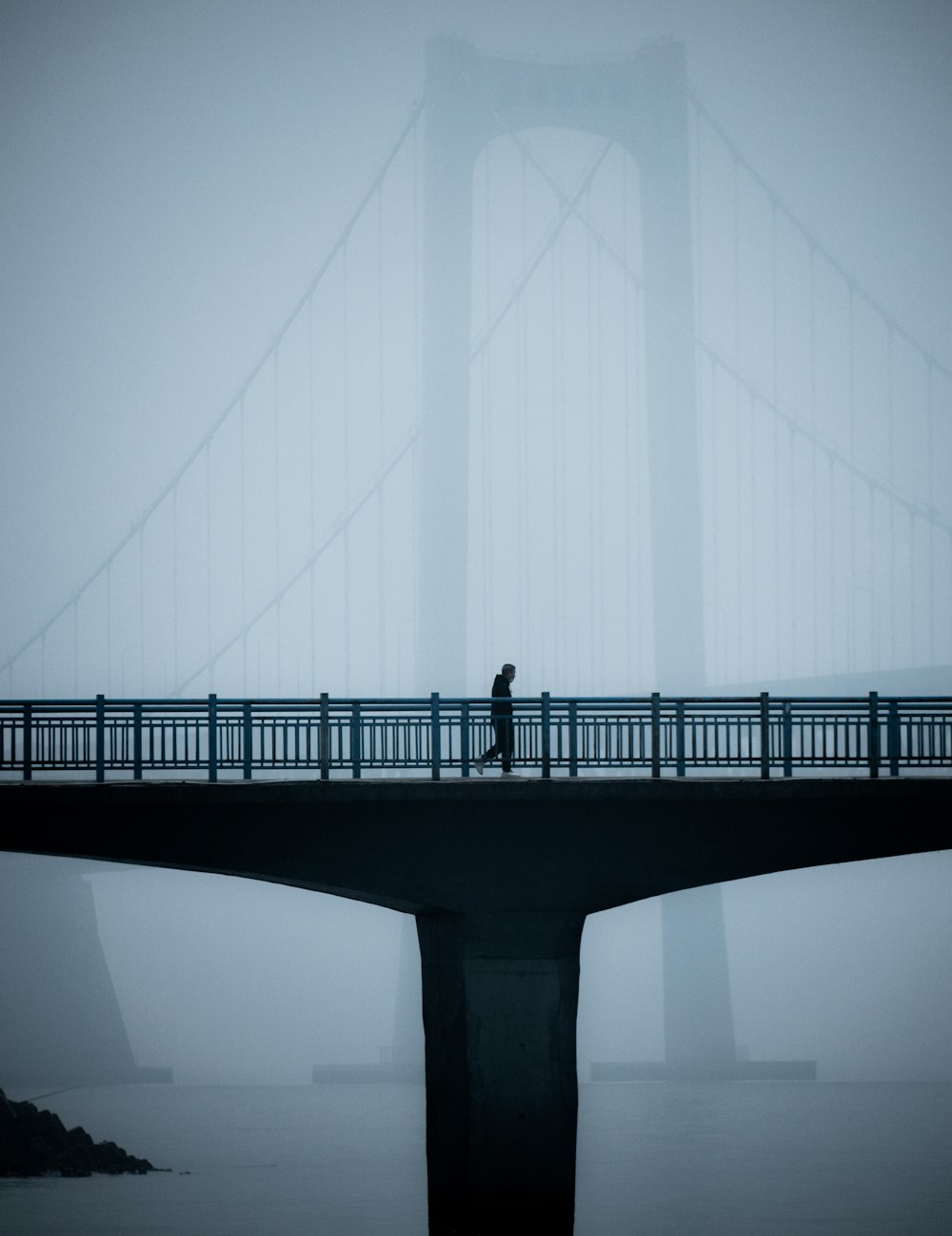 a person walking across a bridge in the fog