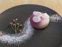 Close-up of a beautifully plated dessert with pink frosting and elegant calligraphy on a menu.