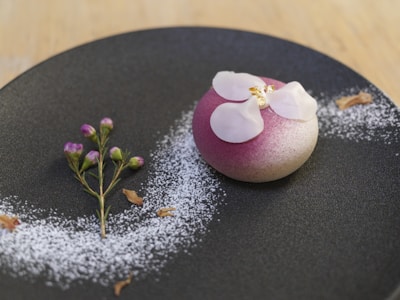 Close-up of a beautifully plated dessert with pink frosting and elegant calligraphy on a menu.