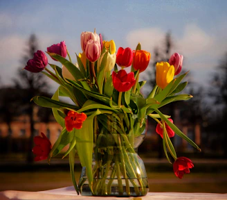 A round luxury flower vase in deep blue ceramic filled with vibrant tulips.
