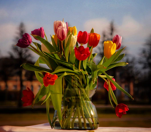 A round luxury flower vase in deep blue ceramic filled with vibrant tulips.