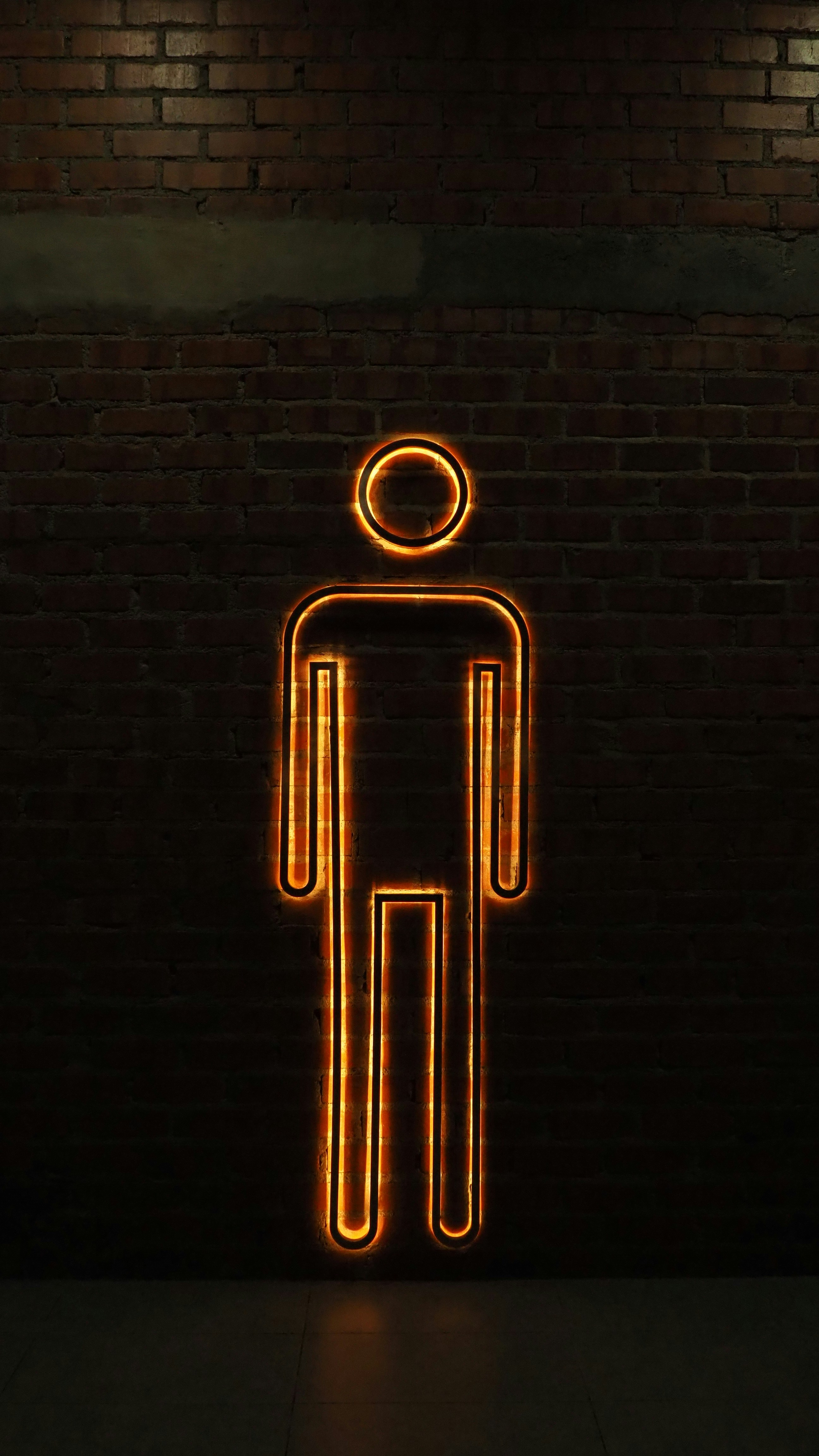 a neon sign with a man standing in front of a brick wall