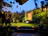 A serene garden nook with comfortable seating surrounded by lush green plants and soft lighting at dusk.