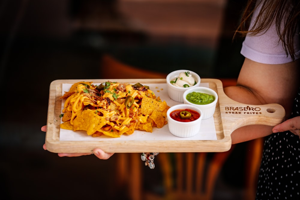 a person holding a plate of food with guacamole and salsa