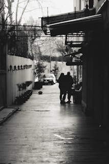 A tense confrontation between two characters in a rain-soaked street, faces barely visible