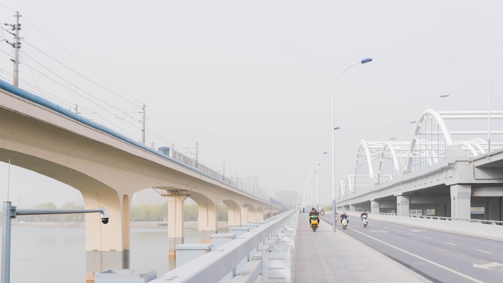 a couple of people walking down a street next to a bridge