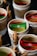 A collection of small cups hold assorted tea bags, including a prominent green and yellow Twinings packet. Some cups are tied with twine and sticks of cinnamon are placed alongside the packets, enhancing the rustic presentation.
