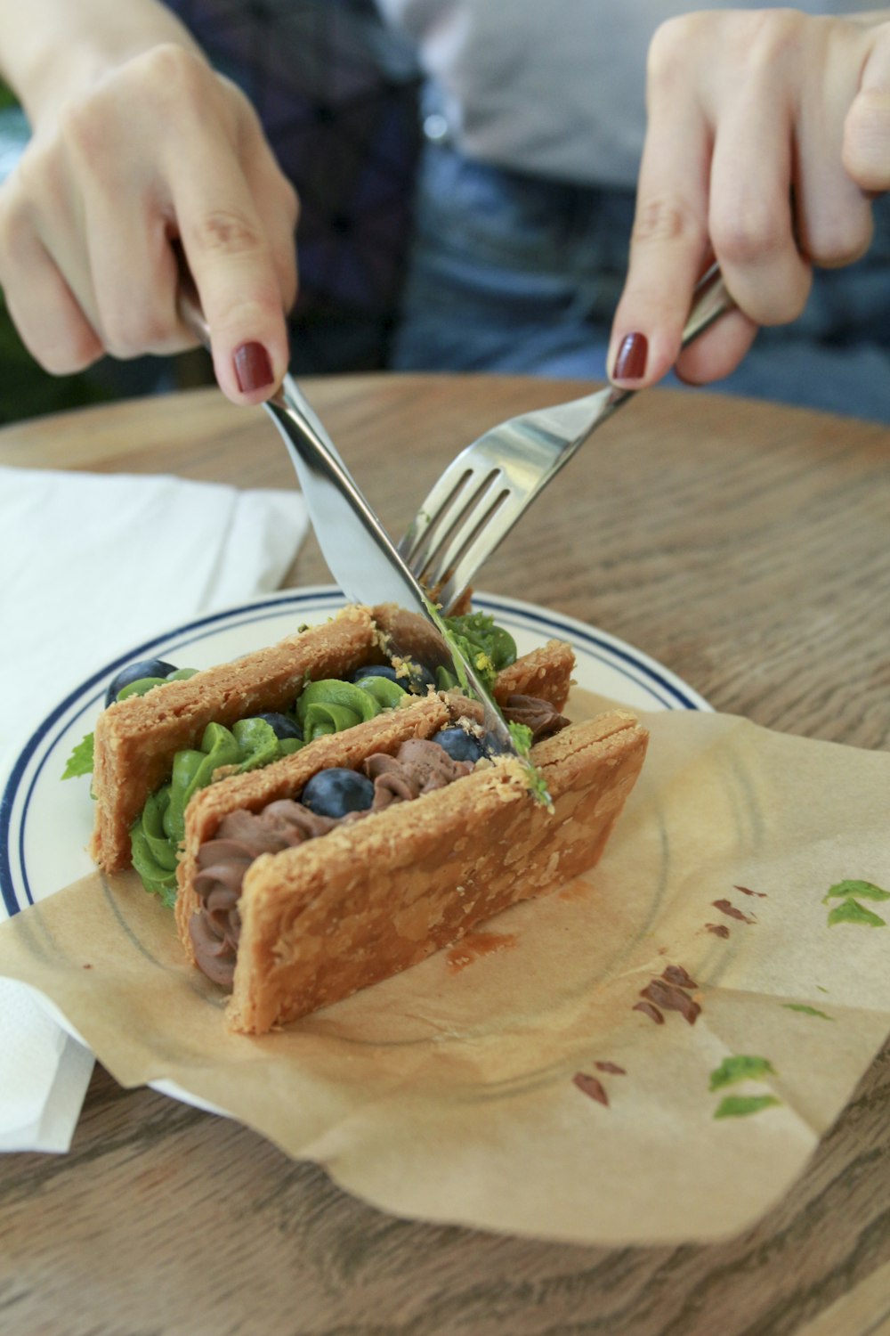 a person cutting into a sandwich with a knife and fork