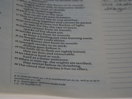 A close-up of a page in a book with text printed in a vertical column. The text appears to be excerpted lines of a poem or scripture, with numbers at the beginning of each line. The text is bordered by a dotted line on the right, with a lined blank space next to it for notes. Some handwritten text is visible at the top right corner.