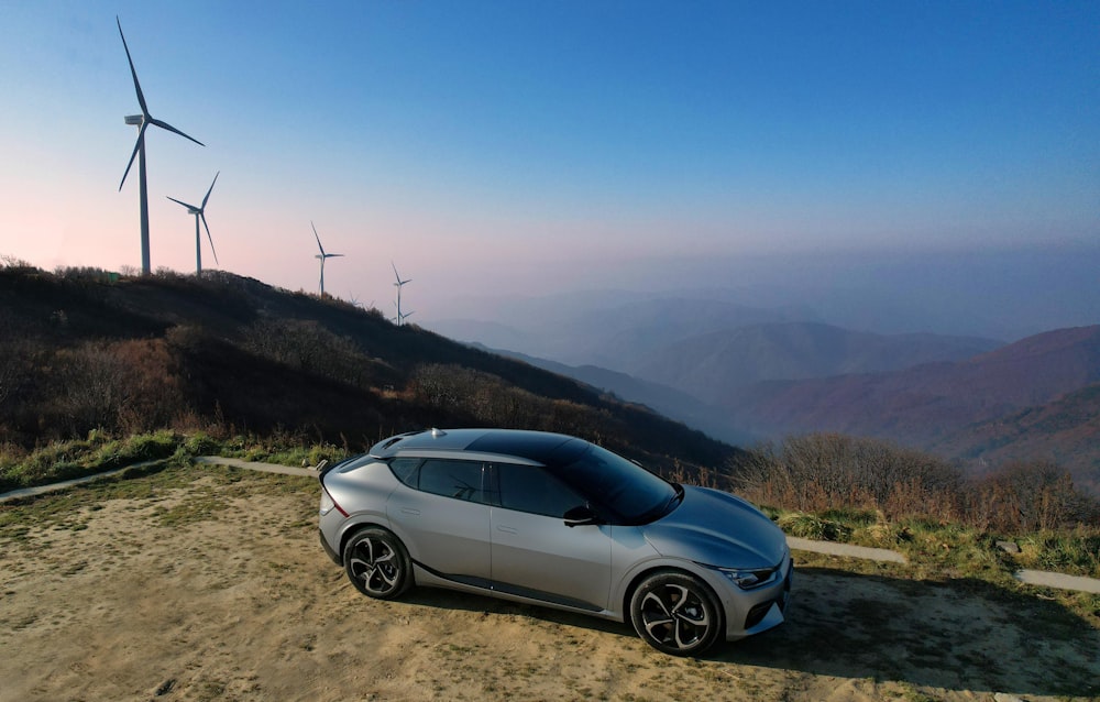 a car parked on a dirt road next to wind turbines