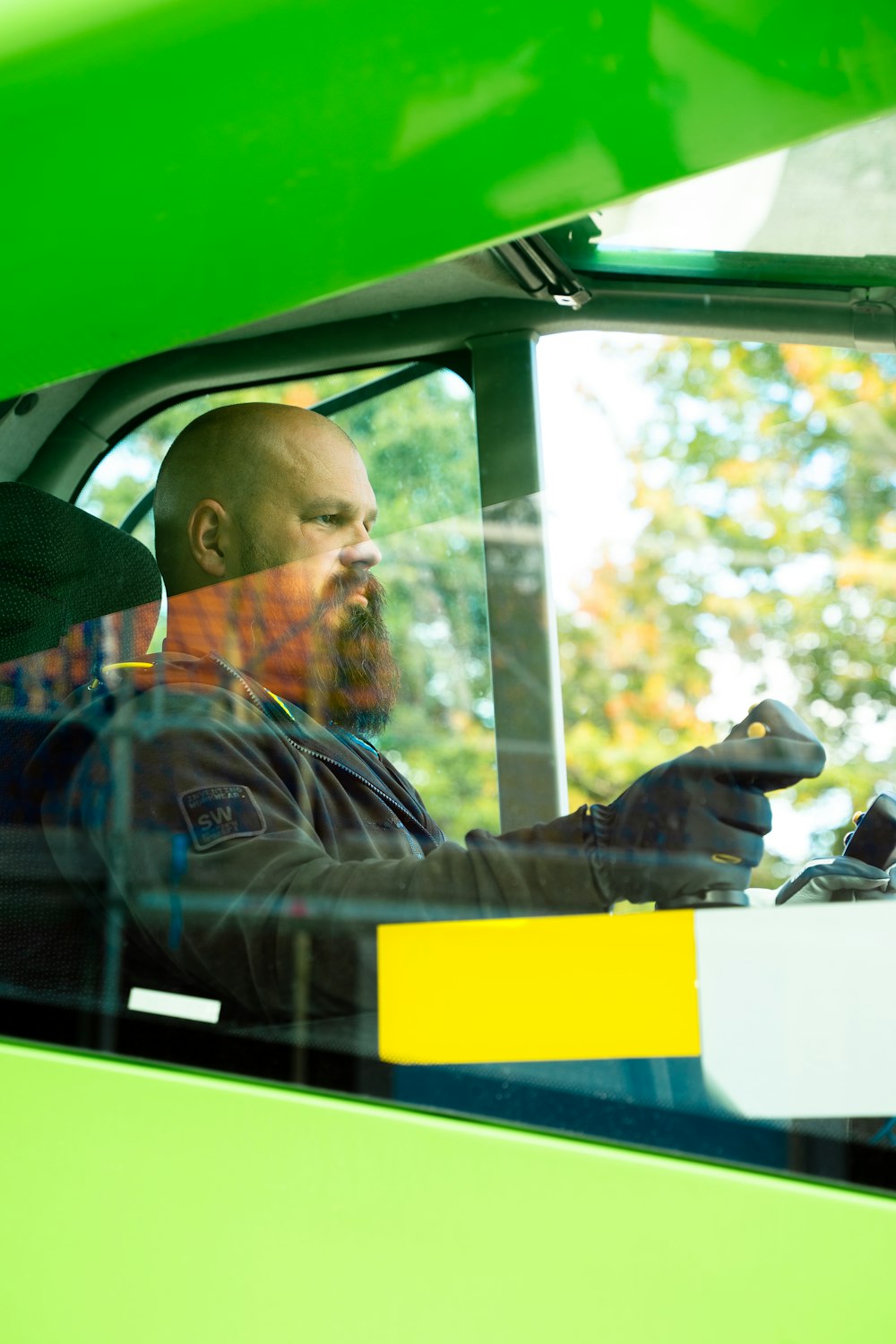 a man sitting in a green truck with his hand on the steering wheel