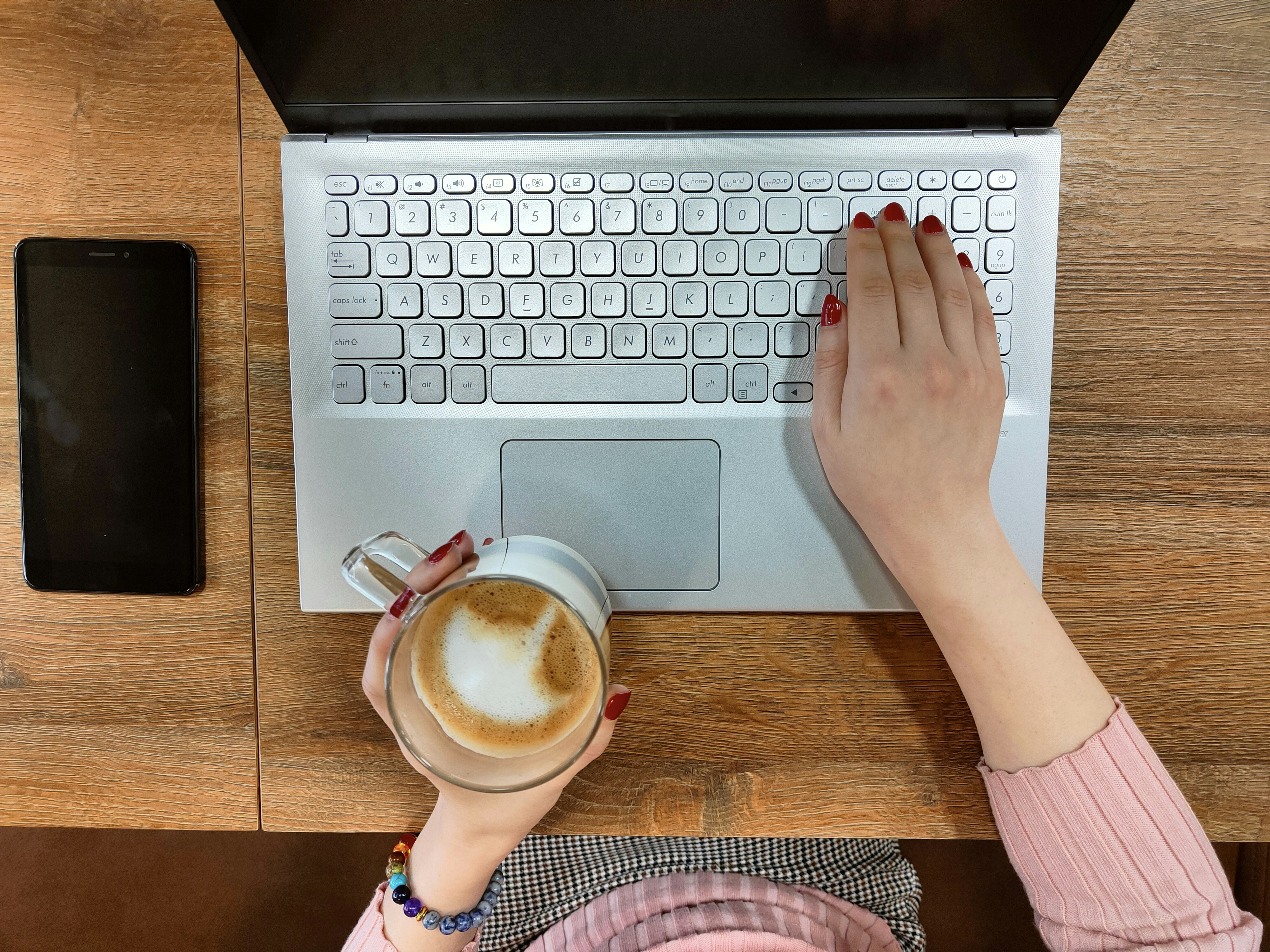 Woman typing on the laptop computer, close up hands with red nails and laptop keyboard in the focus