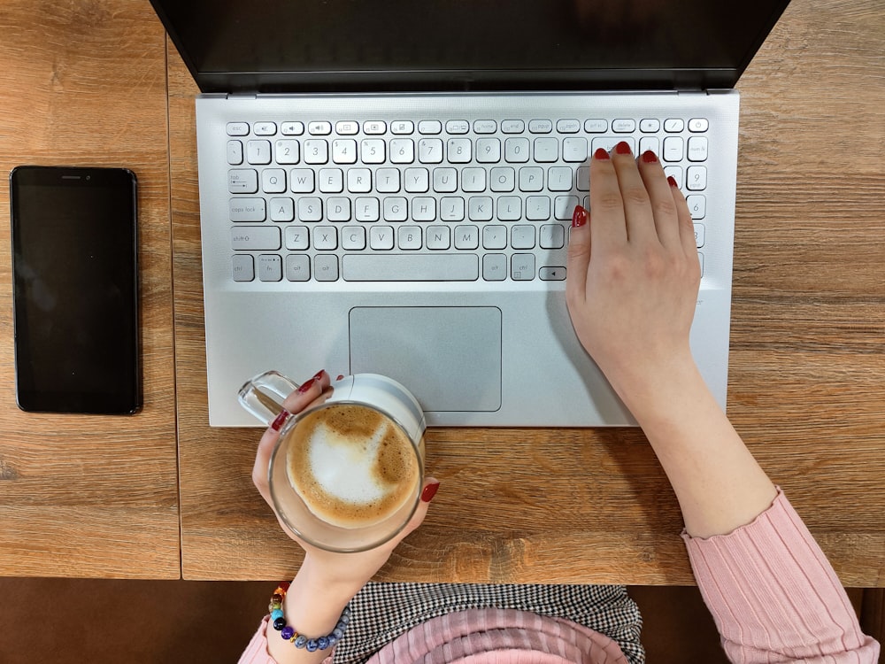 a person typing on a laptop with a cup of coffee