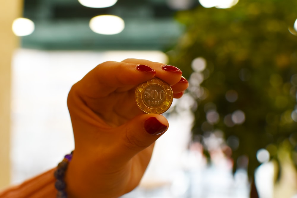 a woman holding a small coin in her hand